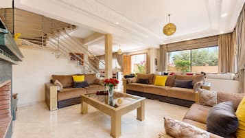 A spacious living room with a large sofa set, a coffee table, and a staircase.