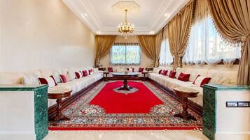 Un salon élégant, avec un tapis rouge, des canapés blancs et un lustre.