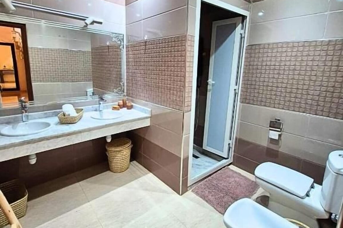 Un baño moderno con lavamanos dobles, inodoro y zona de ducha.