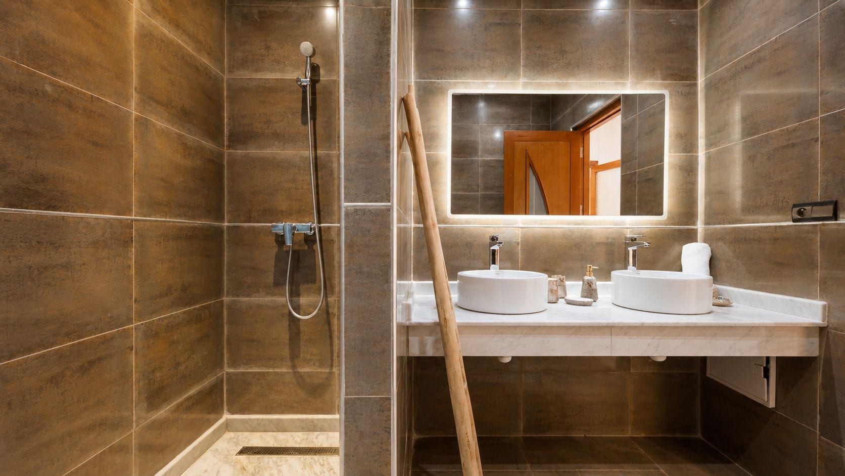 Ein modernes Badezimmer mit barrierefreier Dusche, einem großen Spiegel und einem Waschtisch mit zwei Becken.