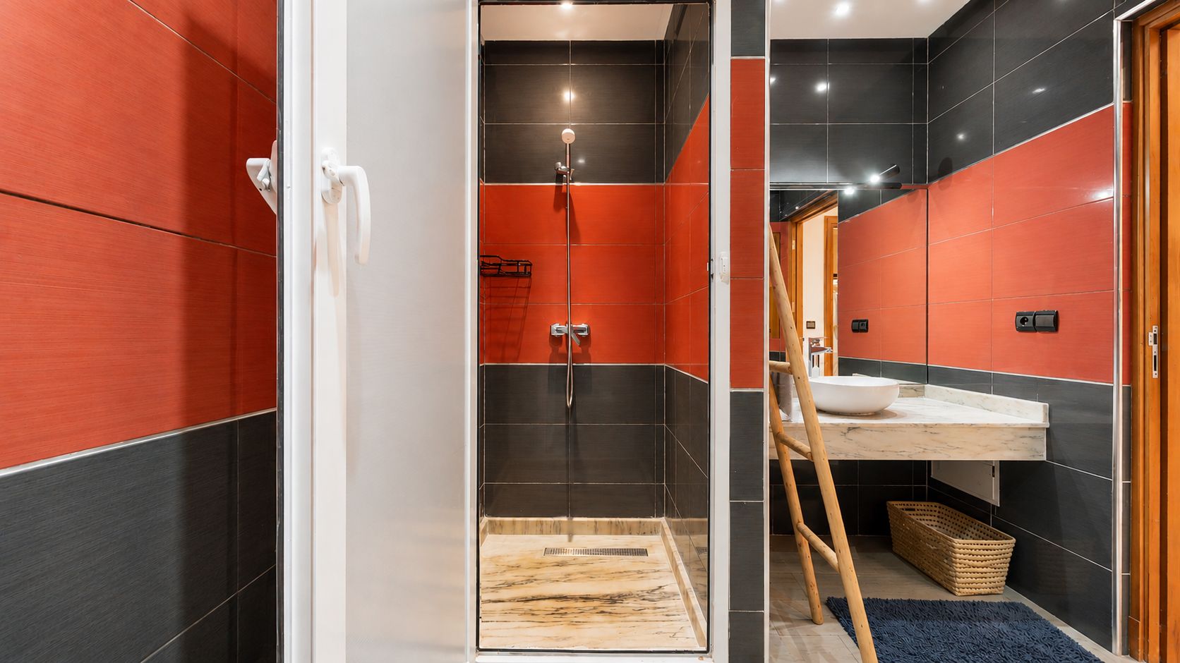 A modern bathroom with a shower, a sink, and a wooden ladder.