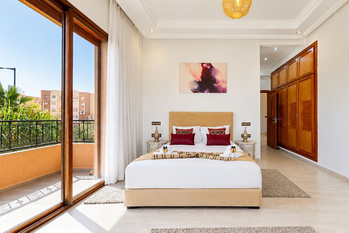 Un dormitorio amplio con una cama grande, vistas de la ciudad y un balcón.