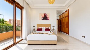 Un dormitorio amplio con una cama grande, vistas de la ciudad y un balcón.