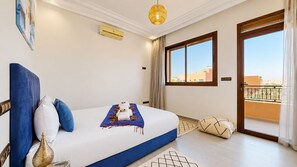 A hotel room with a bed, a window, a balcony, and a view of the city. - Villa Amroth (Marrakech)