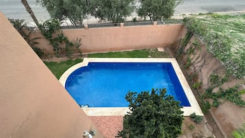 Ein rechteckiger Pool mit einer gefliesten Kante, umgeben von einer niedrigen Mauer und Vegetation.