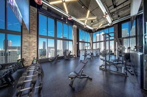 A gym with various exercise equipment, large windows, and a city view. - Luxury 2BR Retreat - Water Views, Pool & Walk to Bayside (Miami)