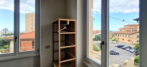 A corner of a room with a wooden shelf against a window, overlooking a street with buildings and parked cars. - City / Village Apartment in Viareggio with 2 bedrooms sleeps 5 (Viareggio)