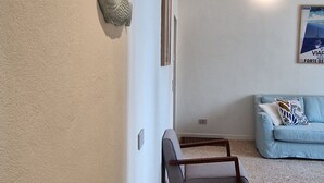 A room with a light blue sofa, a small wooden chair, and decorative fish wall art. - City / Village Apartment in Viareggio with 2 bedrooms sleeps 5 (Viareggio)