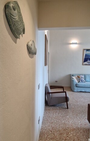 A room with a light blue sofa, a small wooden chair, and decorative fish wall art. - City / Village Apartment in Viareggio with 2 bedrooms sleeps 5 (Viareggio)