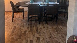 A dining area with a wooden table and chairs, a mirror on the wall, and a window with curtains. - Apartment 'Elea' with Mountain View, Wi-Fi and Air Conditioning (Epanomi)