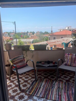 A balcony with two chairs, a small table, and potted plants. - Apartment 'Elea' with Mountain View, Wi-Fi and Air Conditioning (Epanomi)