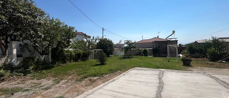 A residential area with a paved driveway, a grassy yard, and a house with a satellite dish.