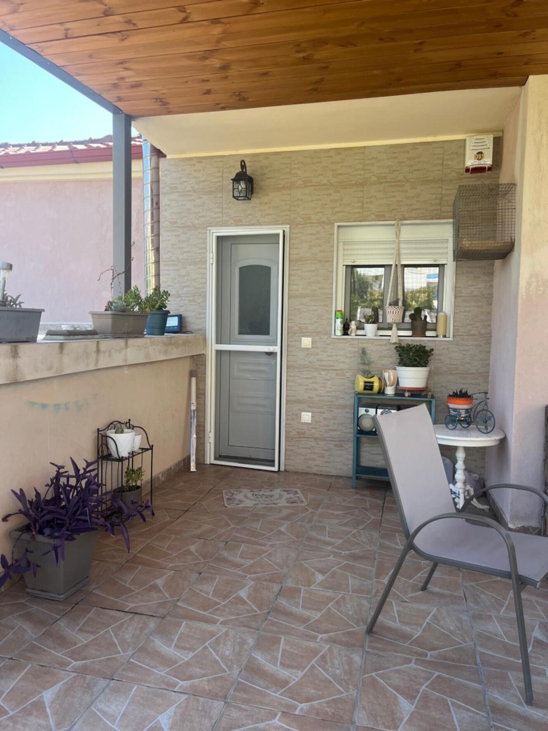 Un patio techado con puerta, una ventana con vistas y una mesa con sillas.