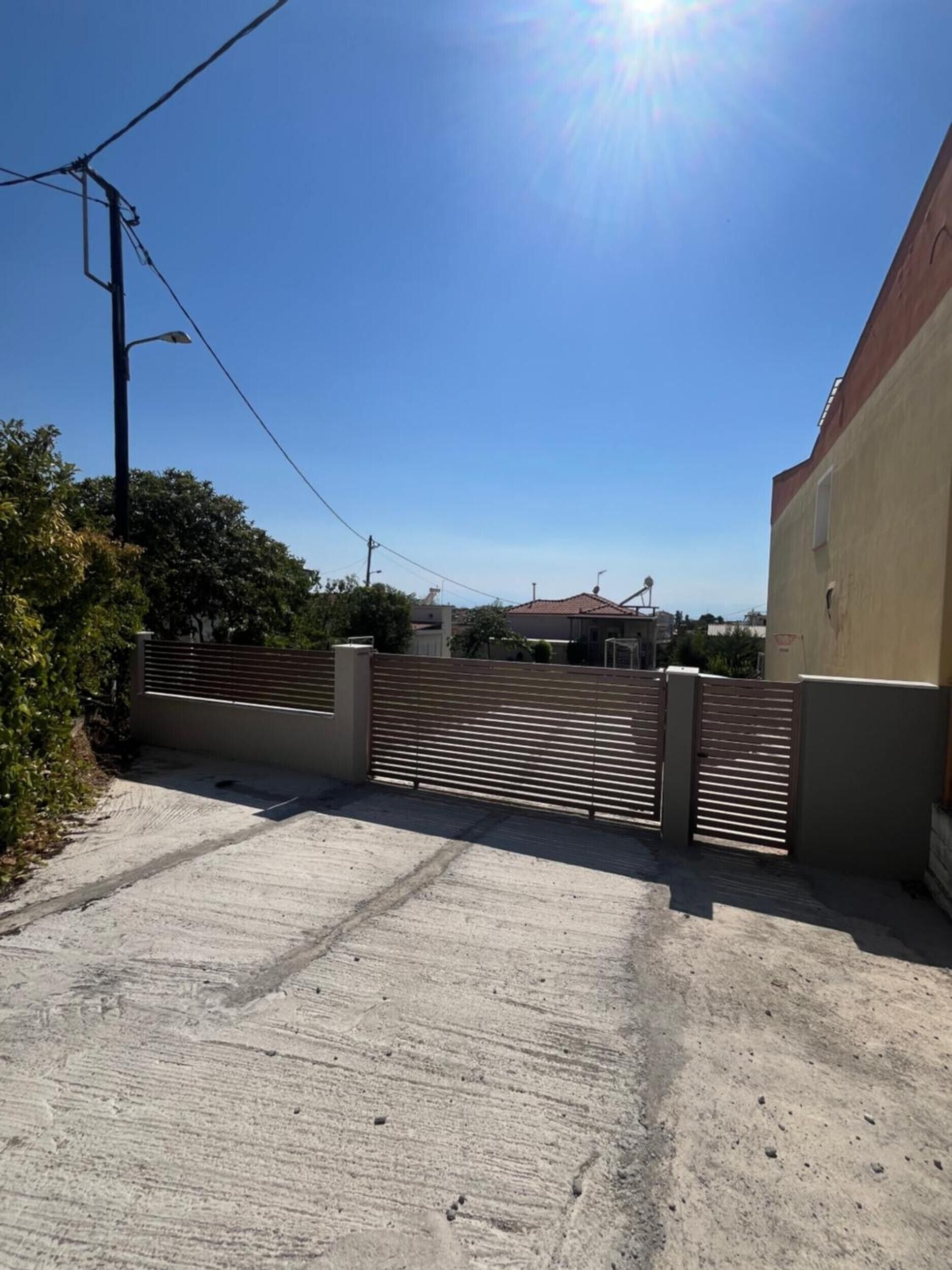 A gated driveway leading to a building with a red-tiled roof.