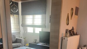 A modern living room with a sofa, coffee table, and television. - Apartment 'Elea' with Mountain View, Wi-Fi and Air Conditioning (Epanomi)