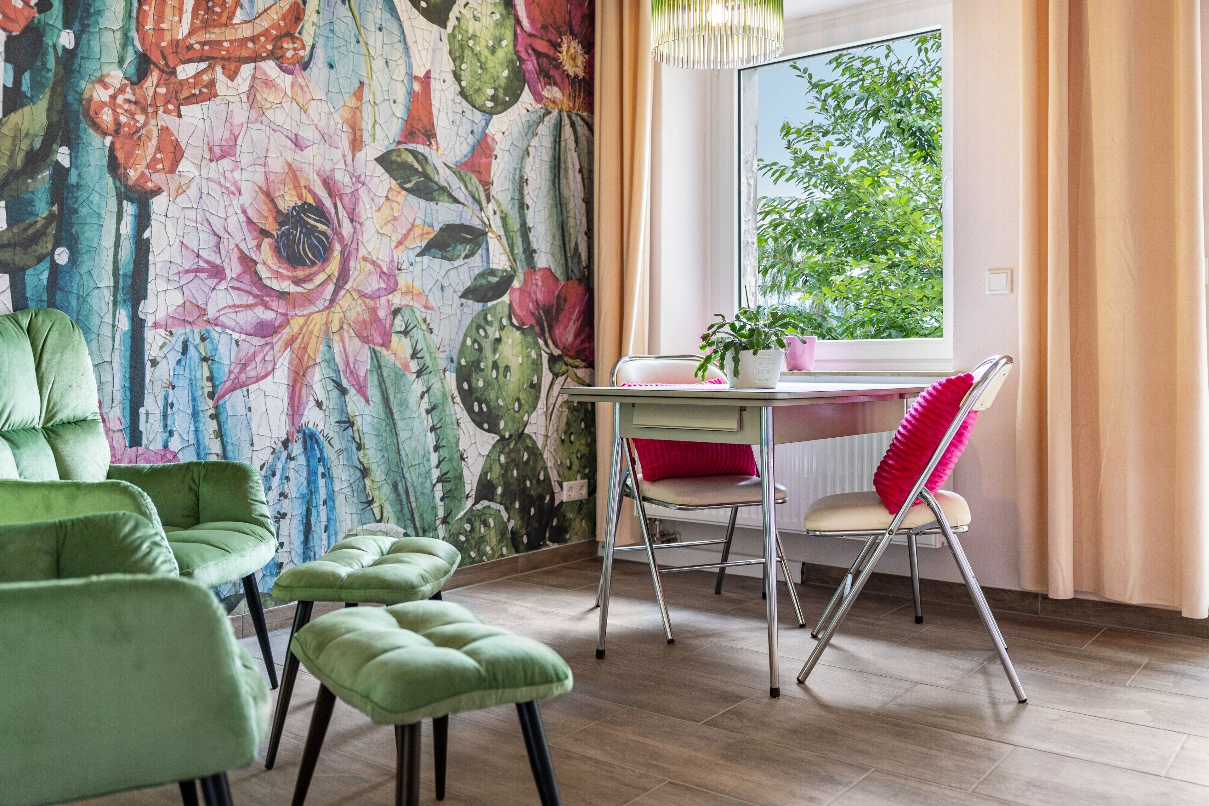 Een kamer met een bloemig behang, een eettafel met stoelen, een raam met gordijnen en een potplant.