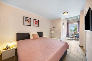 Ein Schlafzimmer mit einem Bett, einem Nachttisch, einem Kleiderhaken und einem Fenster mit Blick.