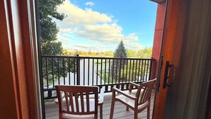 A wooden deck with two chairs and a table, overlooking a landscaped area with trees and a clear sky. - Spacious 3BR/3BA with Jacuzzi, Fireplaces & FREE Waterpark Passes! (Wisconsin Dells)