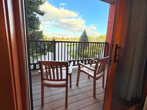 A wooden deck with two chairs and a table, overlooking a landscaped area with trees and a clear sky. - Spacious 3BR/3BA with Jacuzzi, Fireplaces & FREE Waterpark Passes! (Wisconsin Dells)
