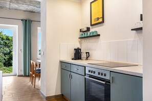Een compacte keuken met een inbouwoven, een koffiezetapparaat en een eethoek met een tafel en stoelen.