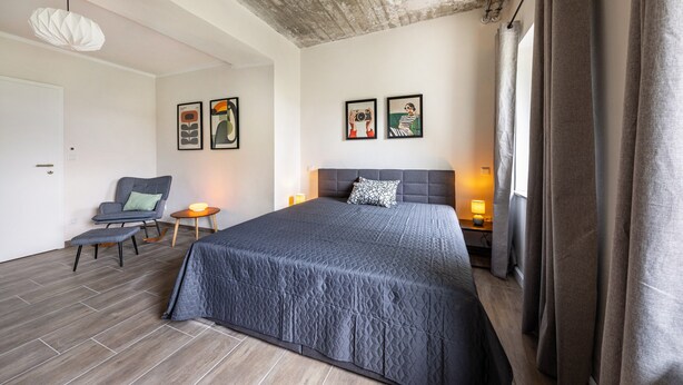 A modern bedroom with a large bed, a chair, and two bedside tables. - Suite Maximilian at Alten Berghotel: Mountain Views, Private Terrace & Wi-Fi (Eslohe)
