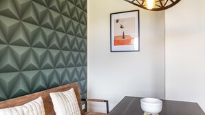 A room with a geometric patterned wall, a framed artwork, a table with a white bowl, and a chair with cushions. - Suite Maximilian at Alten Berghotel: Mountain Views, Private Terrace & Wi-Fi (Eslohe)