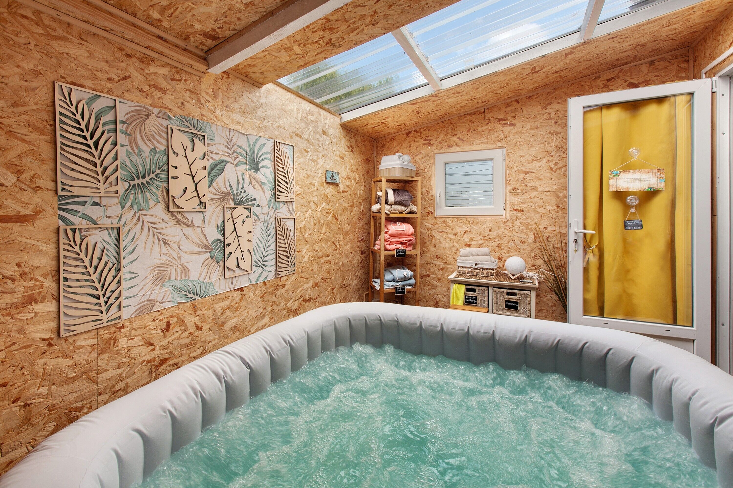 A spa room with a hot tub, wooden walls, and a skylight.