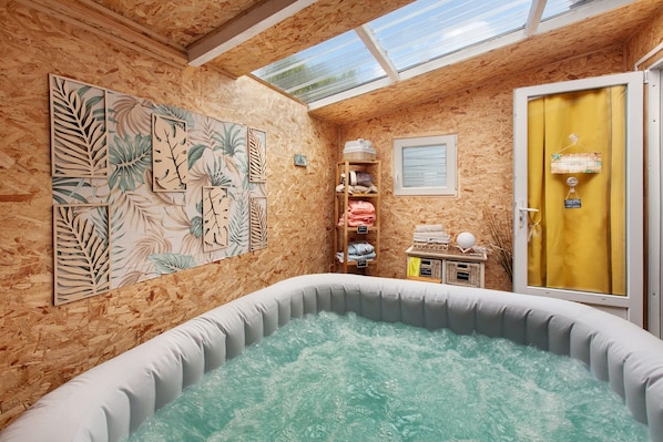 A spa room with a hot tub, wooden walls, and a skylight.