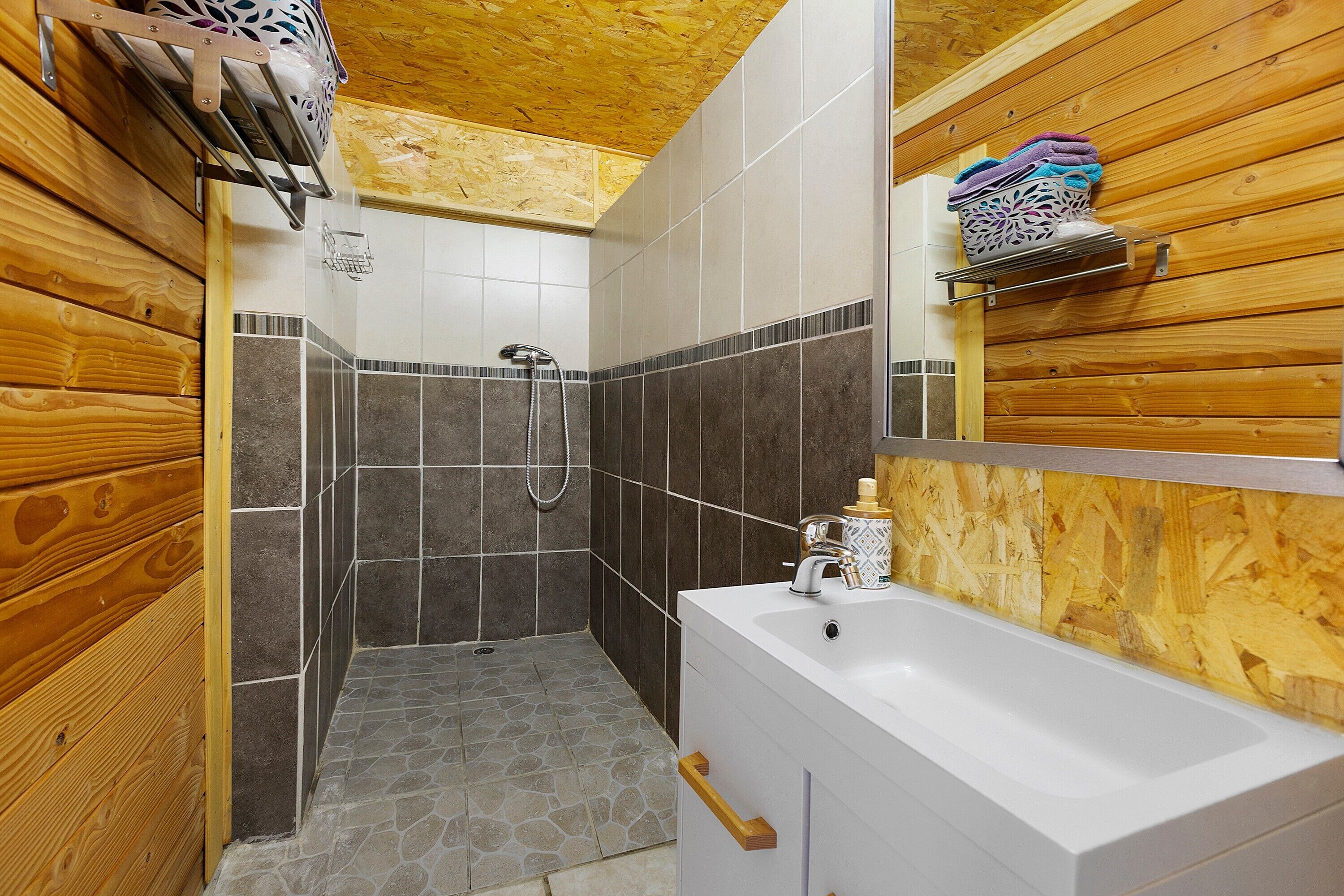 A bathroom with a shower, a sink, and wooden paneling.