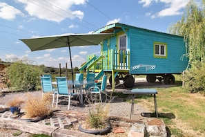 A small, colorful cabin with a porch and outdoor seating area.
