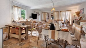 Ein gemütliches Wohnzimmer mit Essbereich, Korbmöbeln und einem Fernseher an der Wand.