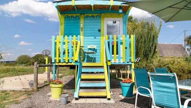 Eine farbenfrohe Holzhütte mit Veranda, Treppe und Tür.