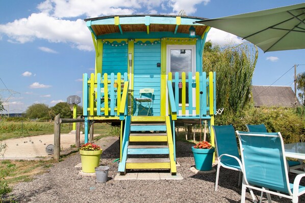 A colorful wooden structure with a porch, steps, and a door.