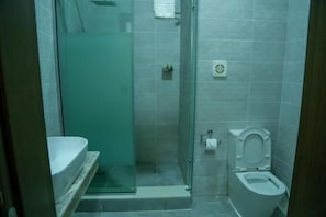 A small, tiled bathroom with a glass shower enclosure, a toilet, and a sink. - Stratton 38 Hotel Asokoro (Abuja)