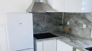 A kitchen with white cabinets, a stainless steel range hood, a marble backsplash, and a built-in sink. - Bright 3-room apartment near the Dôme and the Saint-Just metro station (Marseille)