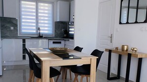 Eine moderne Küche mit weißen Schränken, einer schwarzen Arbeitsplatte und einem Fenster mit Jalousien.