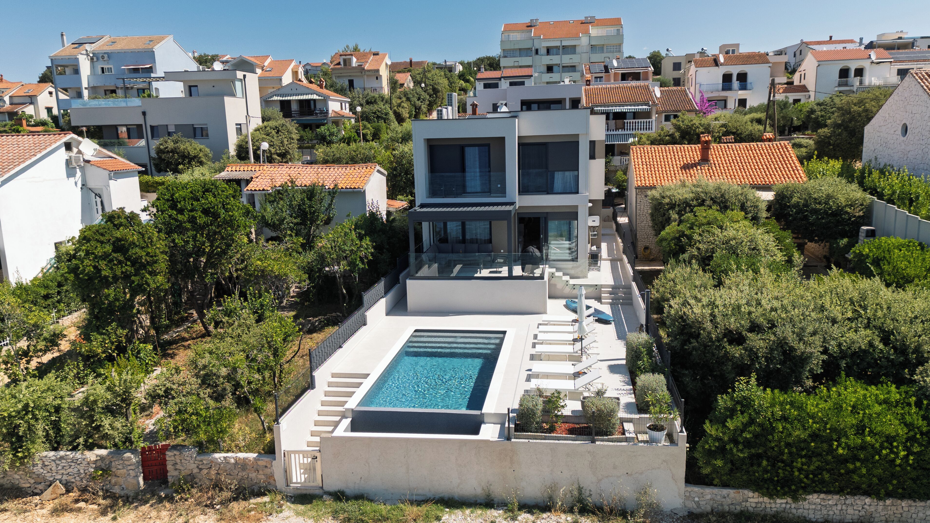 A modern residential building with a rooftop pool and surrounding greenery.