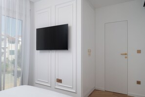 A room with a mounted television, a door with a golden handle, and a window with sheer curtains. - Villa Silvio (Kožino)