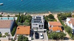 A residential area with a modern house featuring solar panels, a swimming pool, and a view of the sea. - Villa Silvio (Kožino)