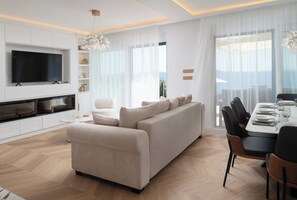 A modern living room with a sofa, TV, and dining area. - Villa Silvio (Kožino)