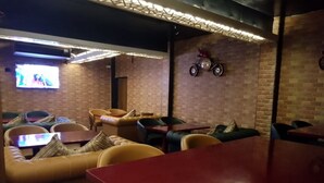 Un área de descanso acogedora con sofás de cuero, una mesa roja y una pantalla de televisión.