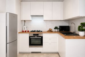 Eine moderne Küche mit weißen Schränken, einem Edelstahlkühlschrank, einem Backofen, einer Mikrowelle und einem Spülbecken.