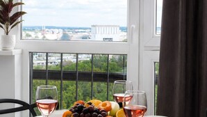A dining table with a fruit bowl and wine glasses, set against a window with a city view. - Lumina 2-room Apartment near Metro  (Warszawa)