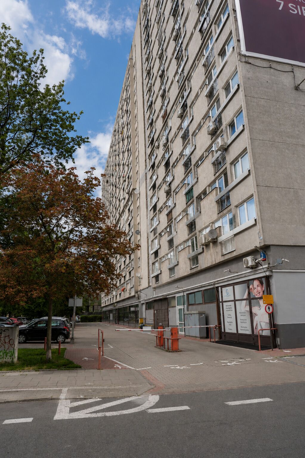 Un edificio residenziale a più piani con balconi, un'area di parcheggio e un percorso pedonale.