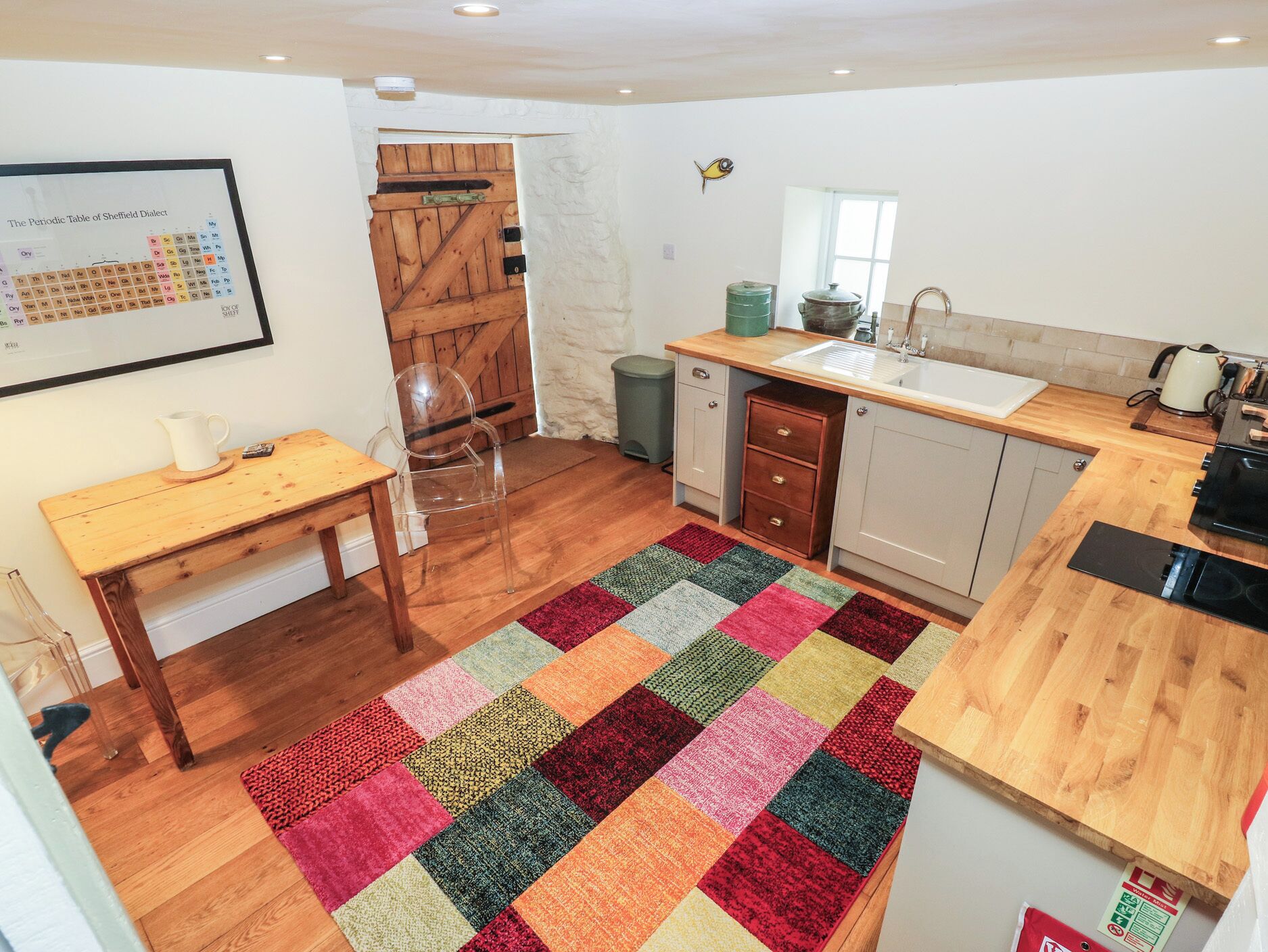 Una cocina funcional con una mesa de madera, un lavamanos y una alfombra colorida.