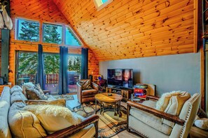 A cozy living room with a large TV, comfortable seating, and a view of the outdoors.