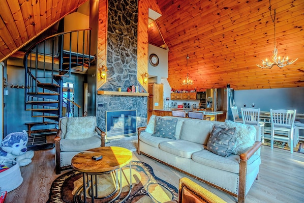 Un interior acogedor con chimenea de piedra, techo de madera y zona de comedor.