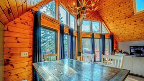 Un intérieur en bois avec une grande table à manger, de nombreuses fenêtres et un lustre.