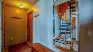 Un couloir avec un banc en bois, un porte-manteau et une porte donnant sur un escalier dont l’intérieur est également en bois.
