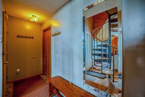 A hallway with a wooden bench, a coat rack, and a door leading to a staircase with a wooden interior.